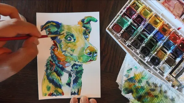 A finished rainbow watercolor dog portrait being detailed with a fine brush