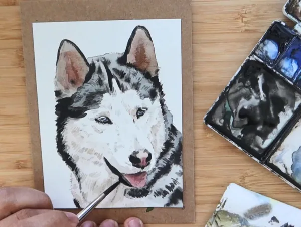 A black and white watercolor portrait of a husky being finished with a brush