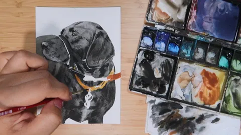 A watercolor portrait of a black Labrador being painted